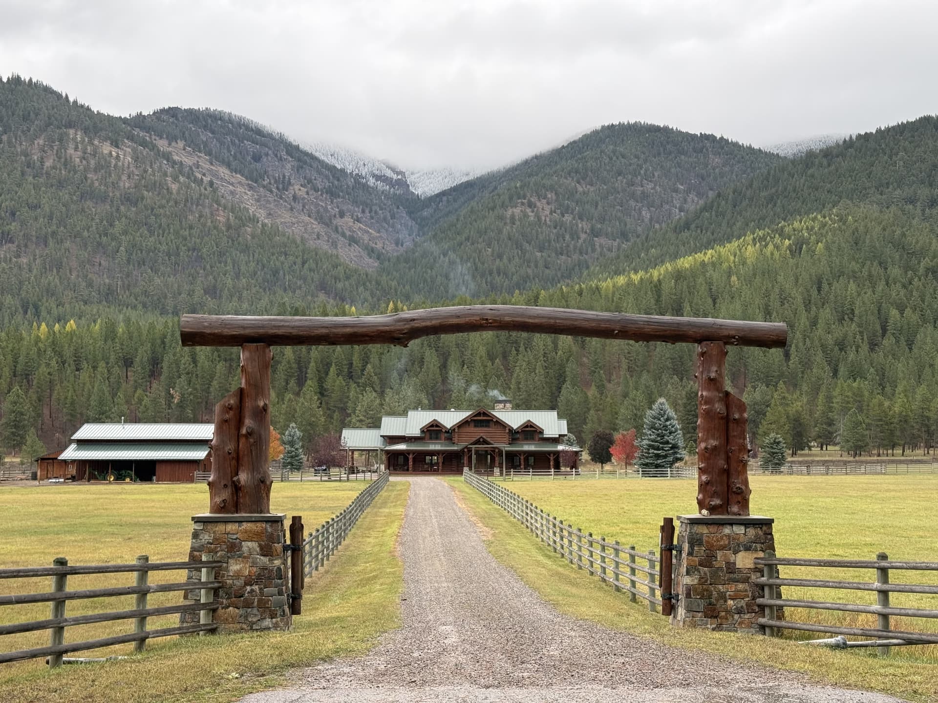Gus Creek Ranch entrance with log archway and mountain backdrop